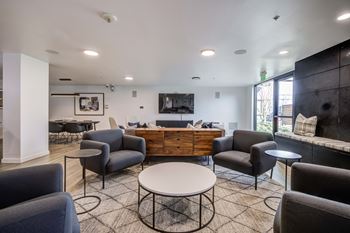 A living room with a white table surrounded by grey chairs.